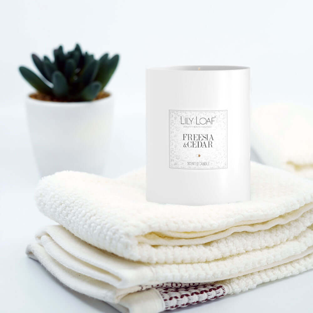Freesia & Cedar Soy Wax Candle paced upon folded towels
