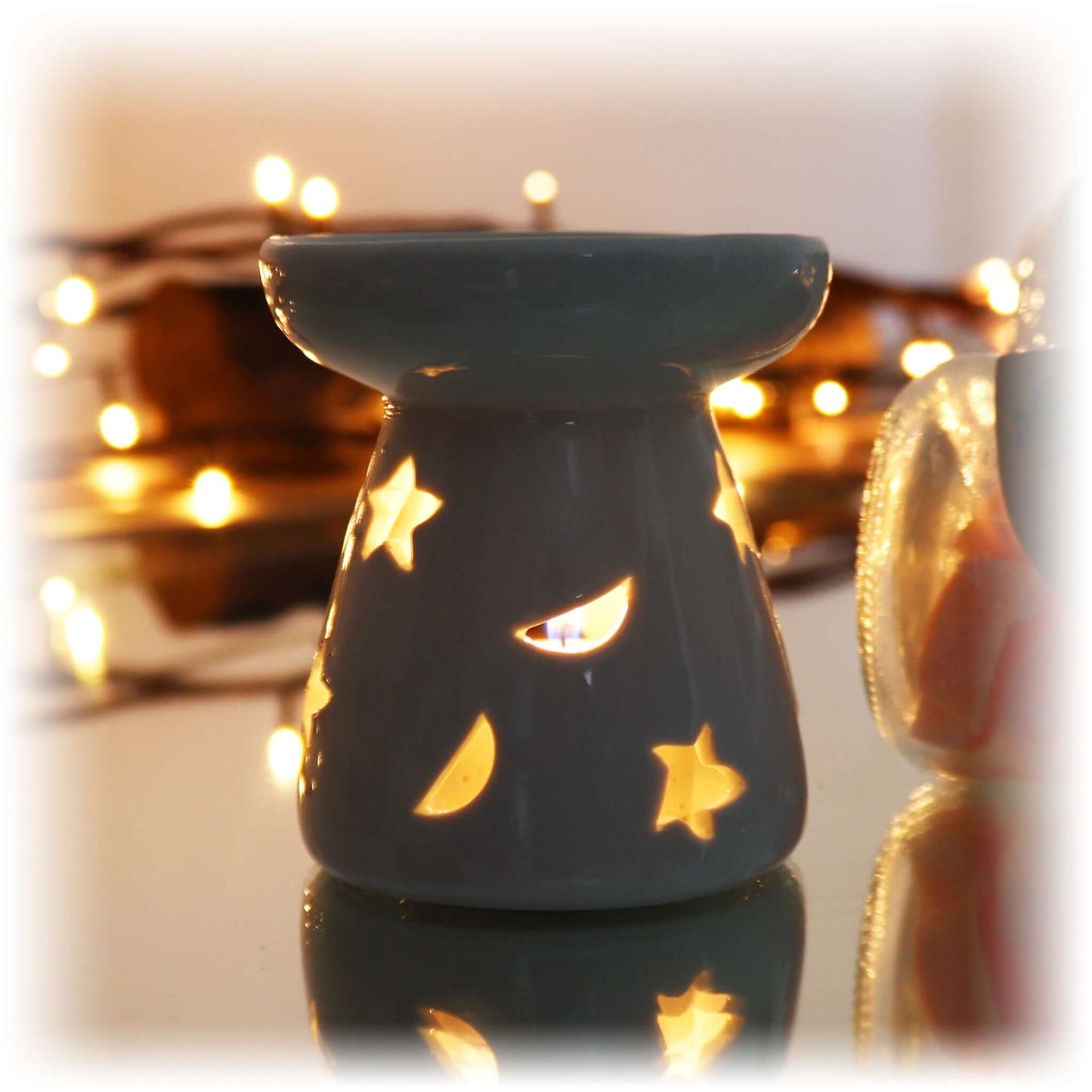 Small white moon and star oil burner lit with a tea light