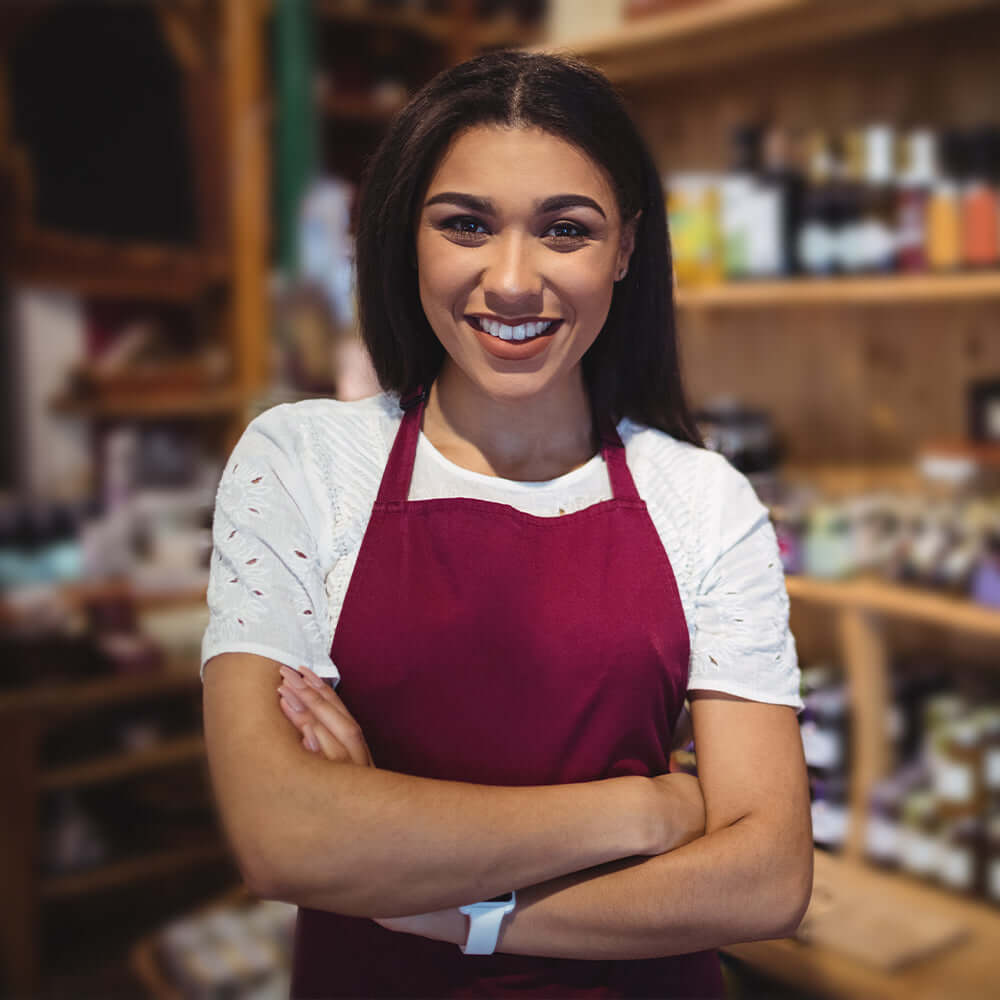 A smiling shop owner in a red apron
