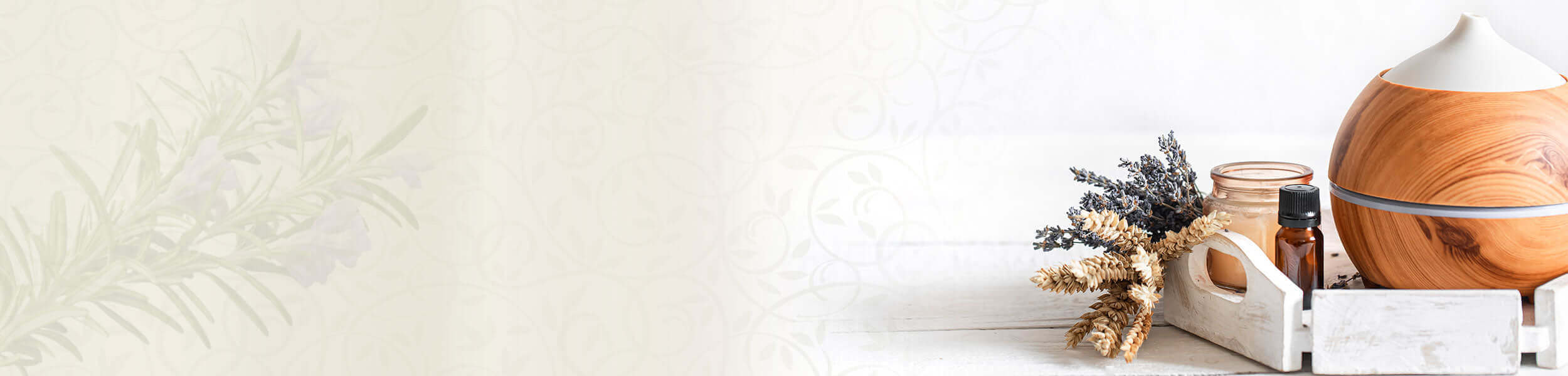 Wooden essential oil diffuser with dried herbs and bottles on a white tray.