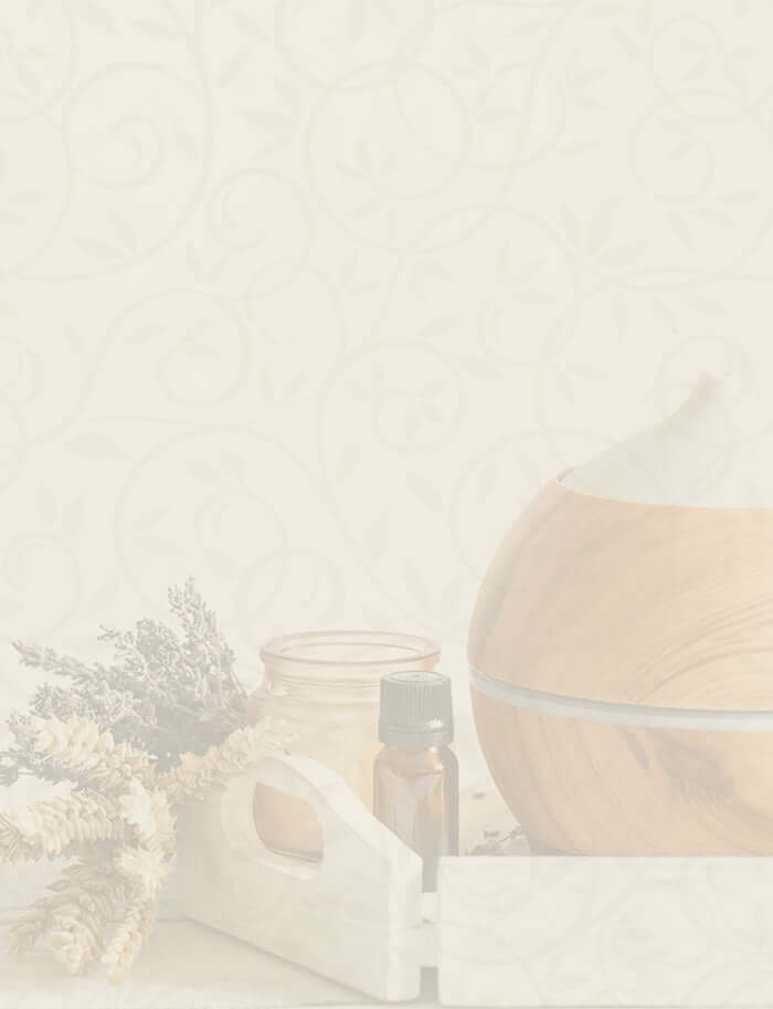 Wooden essential oil diffuser with dried herbs and amber bottle on a soft floral background