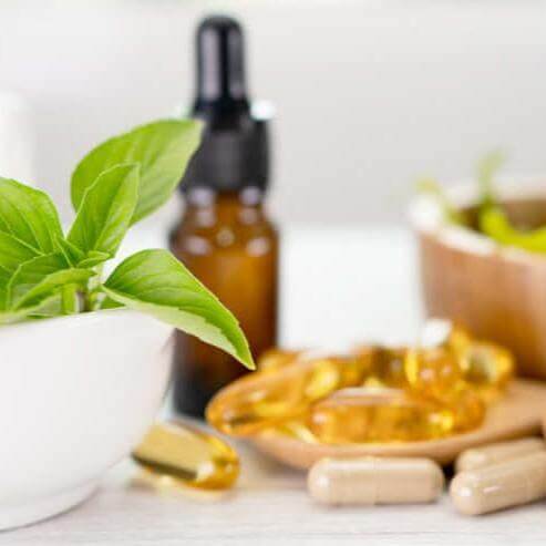 Herbal supplements and capsules with a mortar and pestle, representing Lily & Loaf's commitment to natural health solutions.