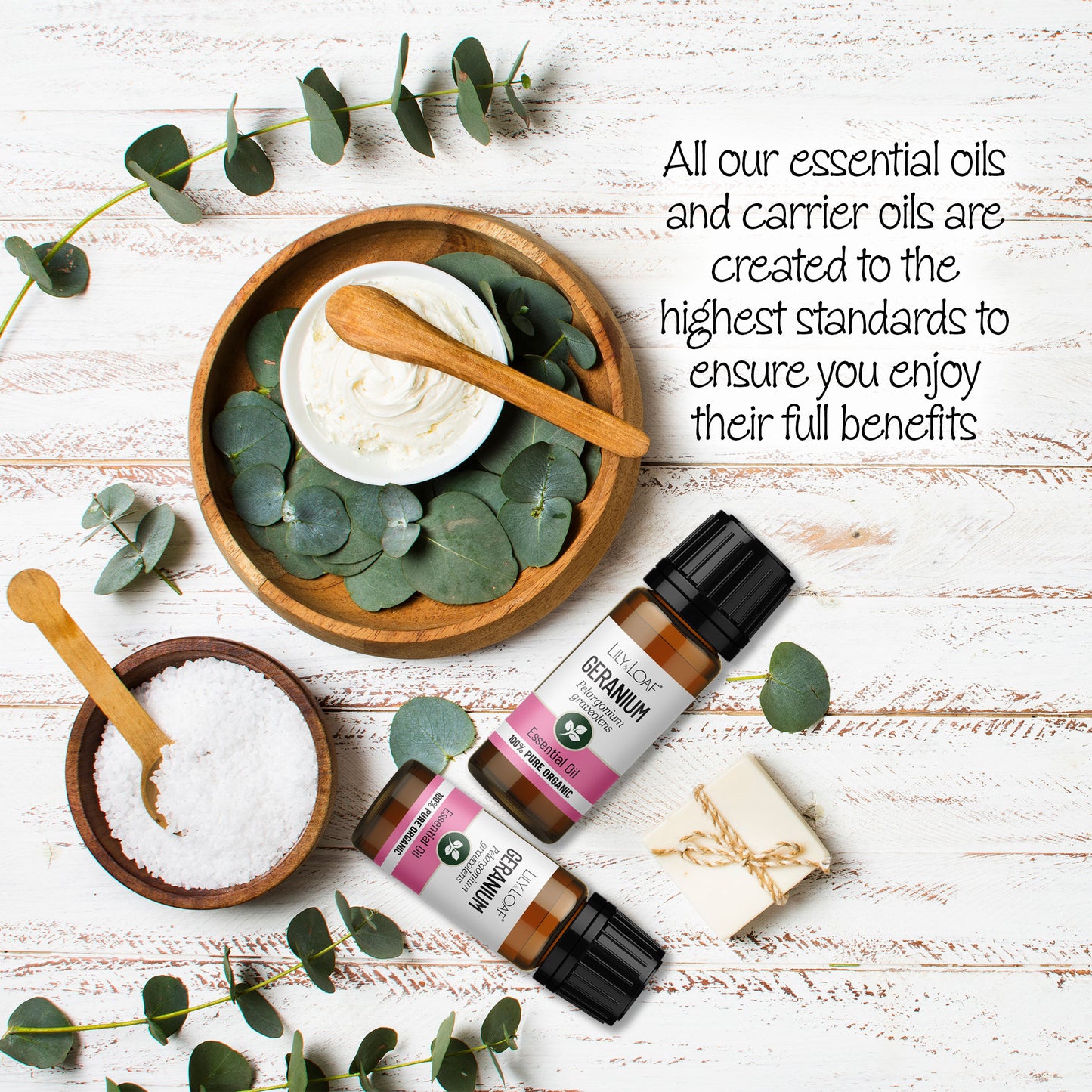 Two 10ml amber Geranium oil bottles with eucalyptus, soap, salt and cream on white wood, highlighting quality and benefits