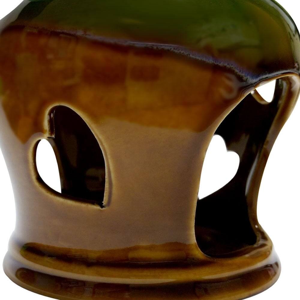 Close-up of brown and green glazed ceramic essential oil burner with heart-shaped cutouts