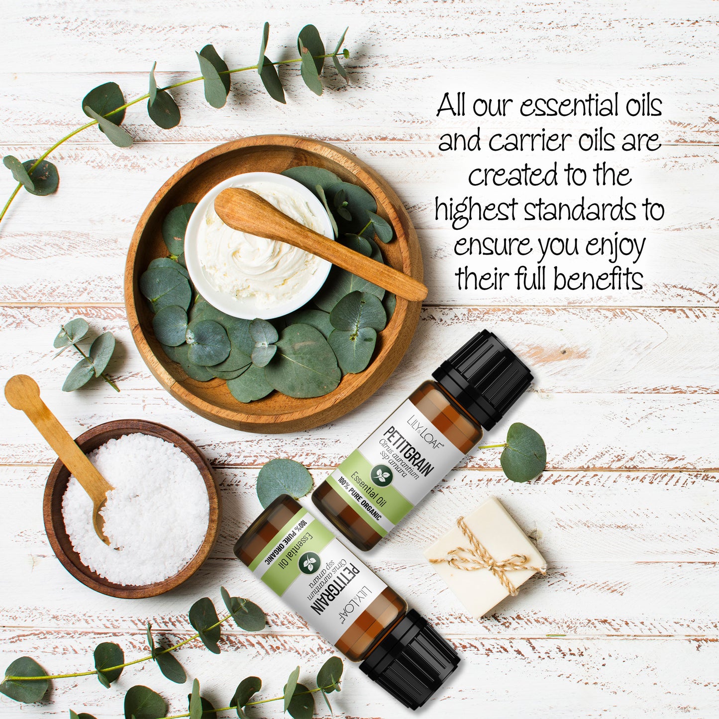 Lily & Loaf Petitgrain essential oil bottles with eucalyptus, cream, salt, and soap on a white wooden surface