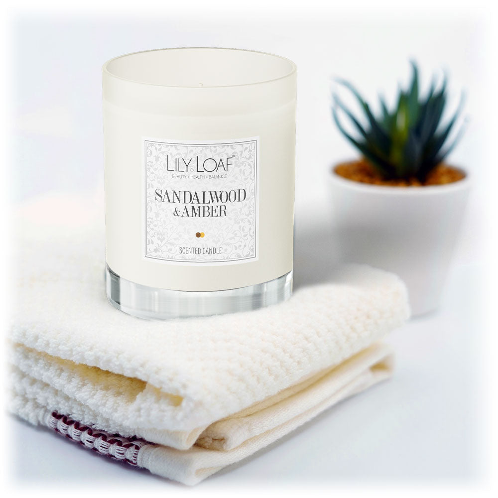 Sandalwood and Amber Soy Wax Candle sat on fresh folded towels