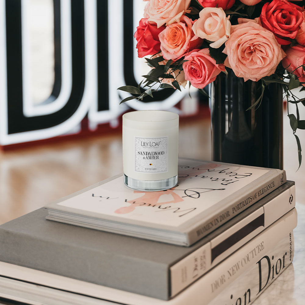 Sandalwood and Amber Soy Wax Candle sat up on a pile of books