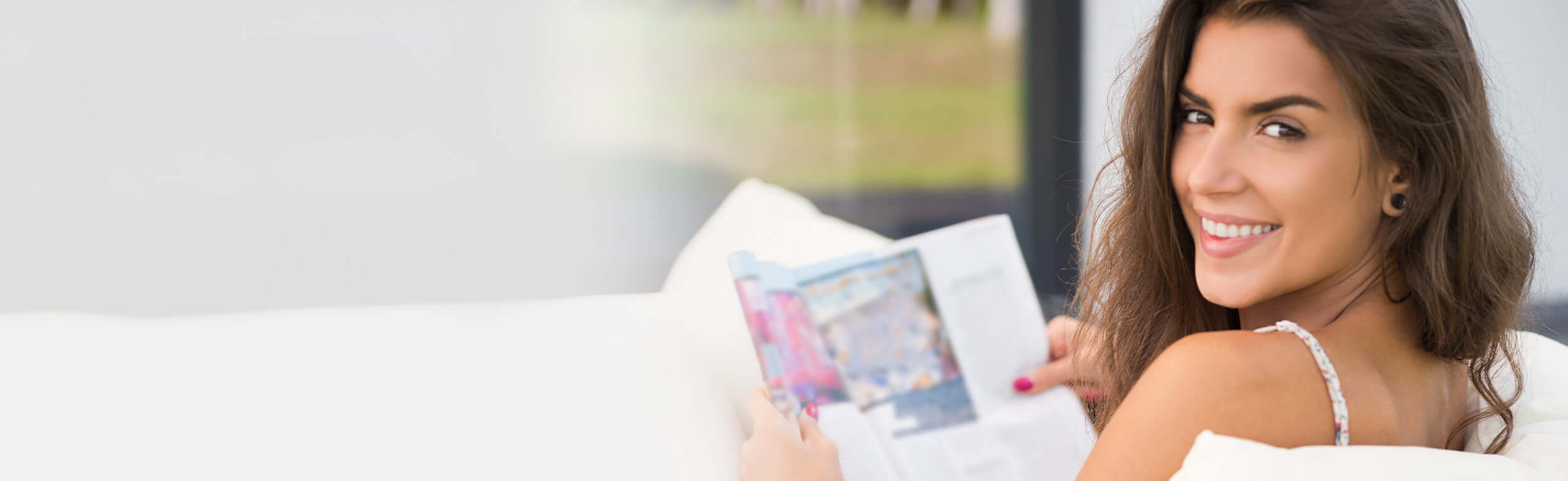 A woman sat outside enjoying reading a magazine