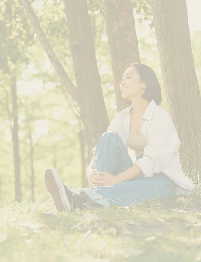 A woman sitting and smiling in the woods 